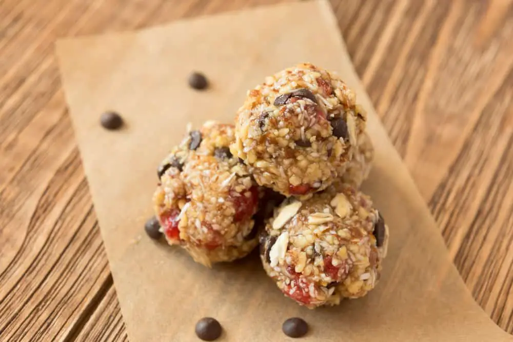 Chocolate chip granola balls on parchment paper on wooden surface