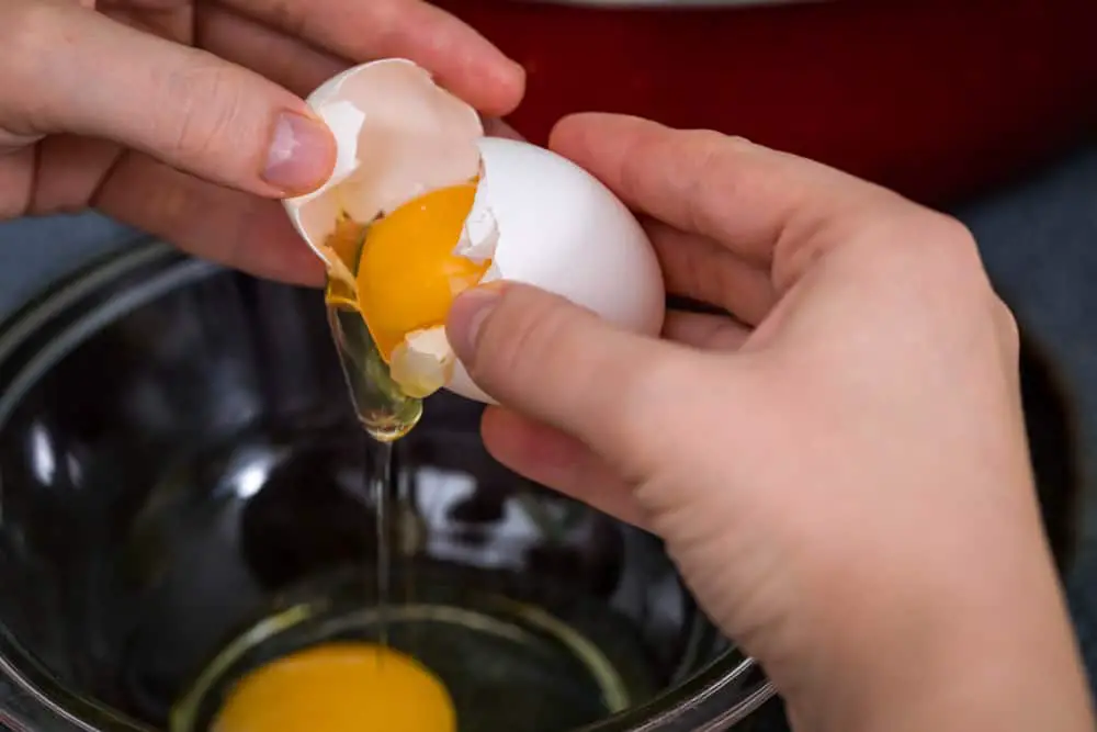 Cracking egg into glass bowl