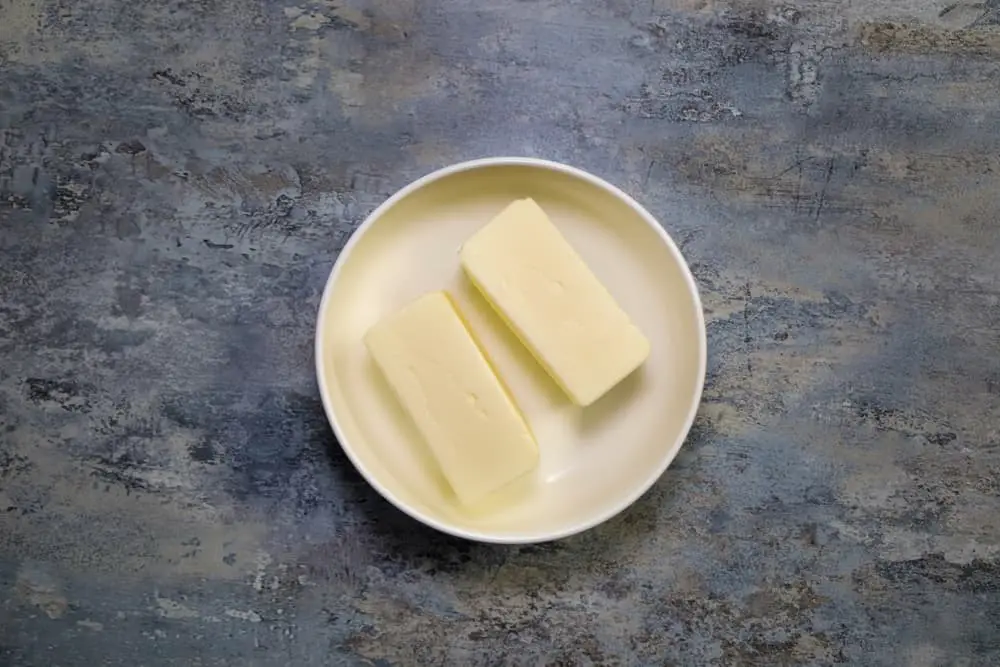 Sticks of softened butter in bowl on counter