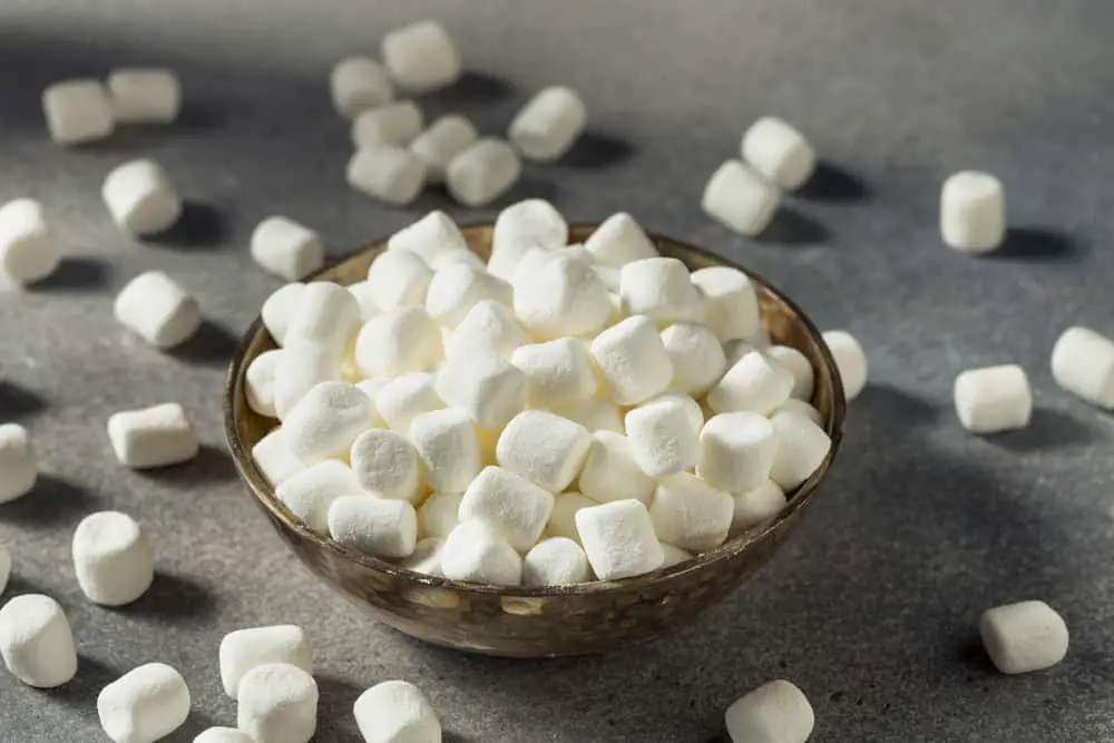 Bowl of mini white marshmallows with others scattered around