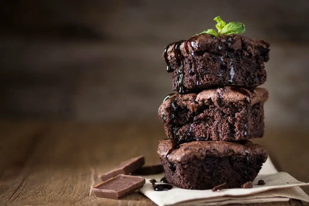 Stack of drizzled chocolate brownies on paper napkin