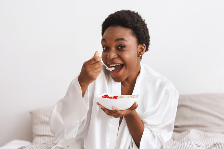 African-American-woman-with-braces-eating-bowl-of-oatmeal-with-fruit
