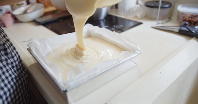 Pouring-fresh-cake-batter-into-lined-pan-for-baking