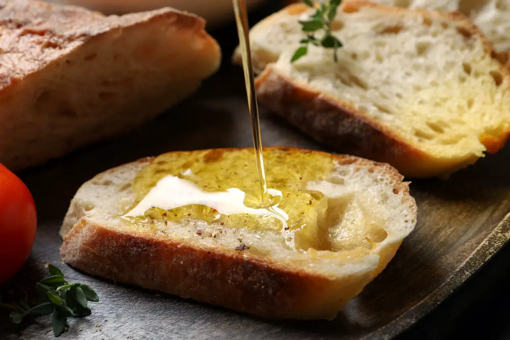 Pouring olive oil on slices of fresh bread