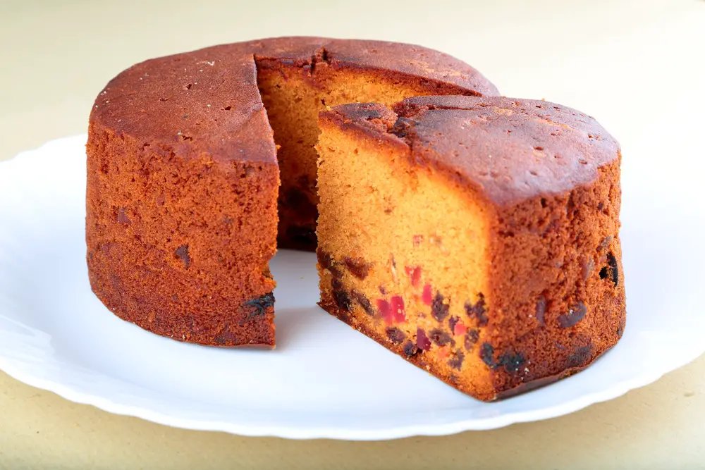 Round plum cake with slice cut out of it looks very moist