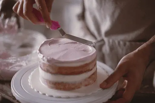Woman icing freshly baked homemade cake