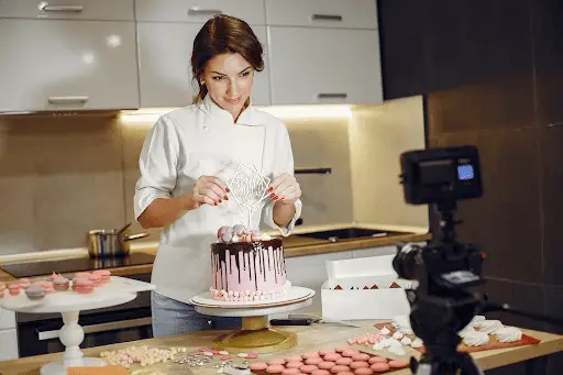 Woman making fancy cake while filming online baking class