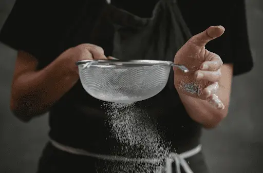Woman sifting flour with mesh strainer