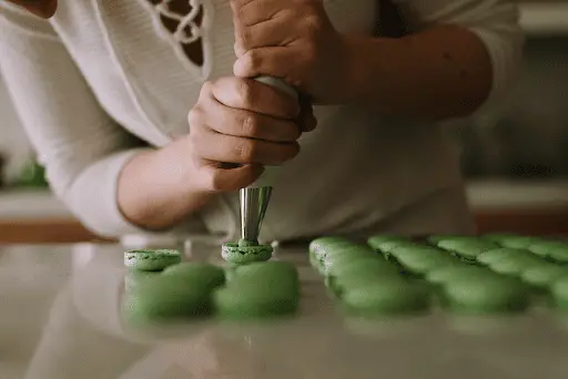 Woman spreading icing on green cupcakes