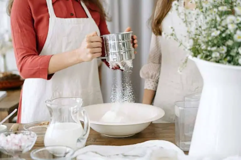 Woman-using-flour-sifter-while-baking-with-daughter