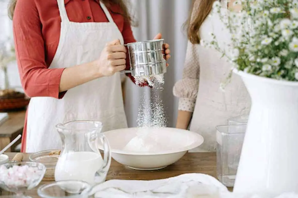 https://daisyflour.com/wp-content/uploads/2023/06/Woman-using-flour-sifter-while-baking-with-daughter-1.jpg